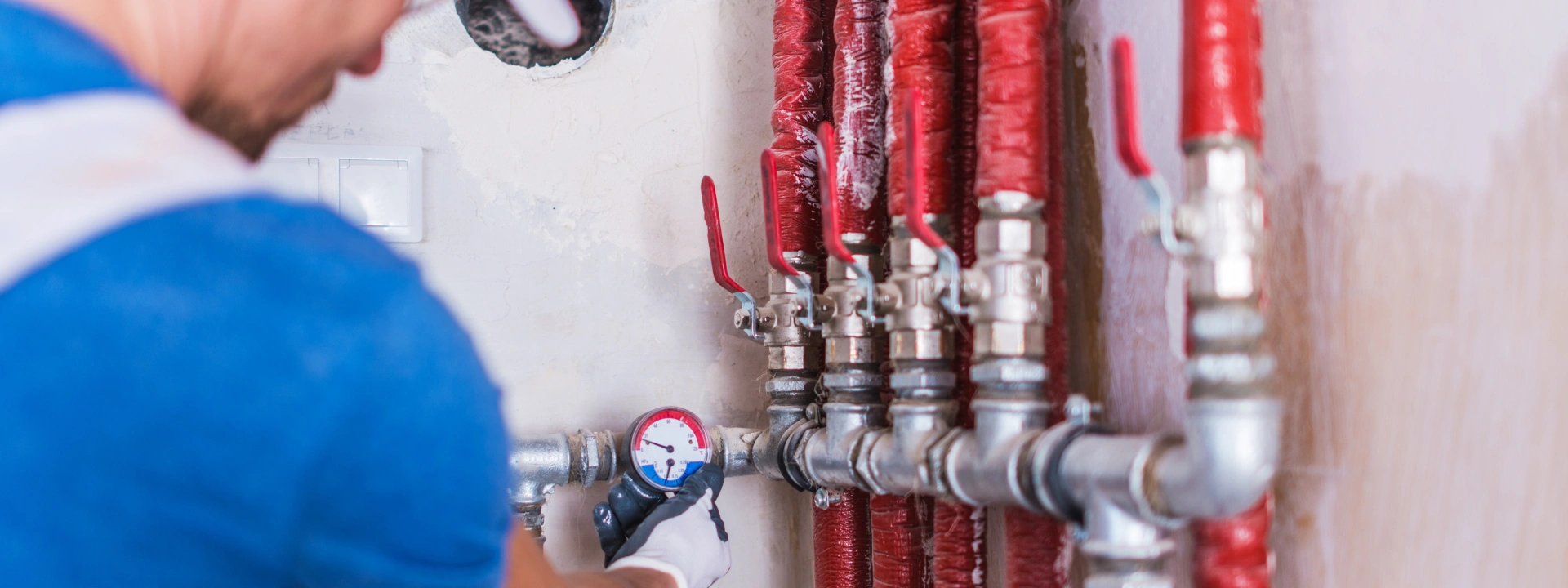 Handyman UAE fixing plumbing system with pressure gauge and red piping
