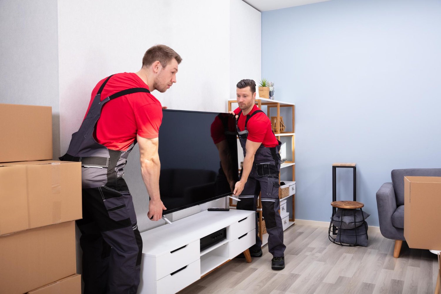Handyman UAE TV installation and moving service with two professionals handling a large TV