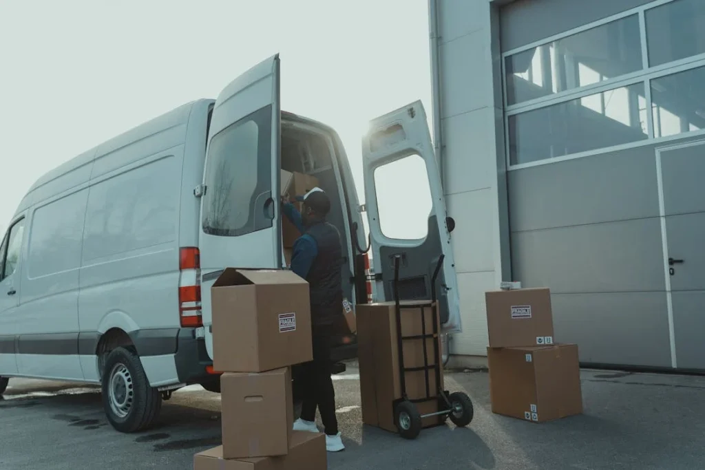 A man is loading boxes into the back of a van, preparing for a move